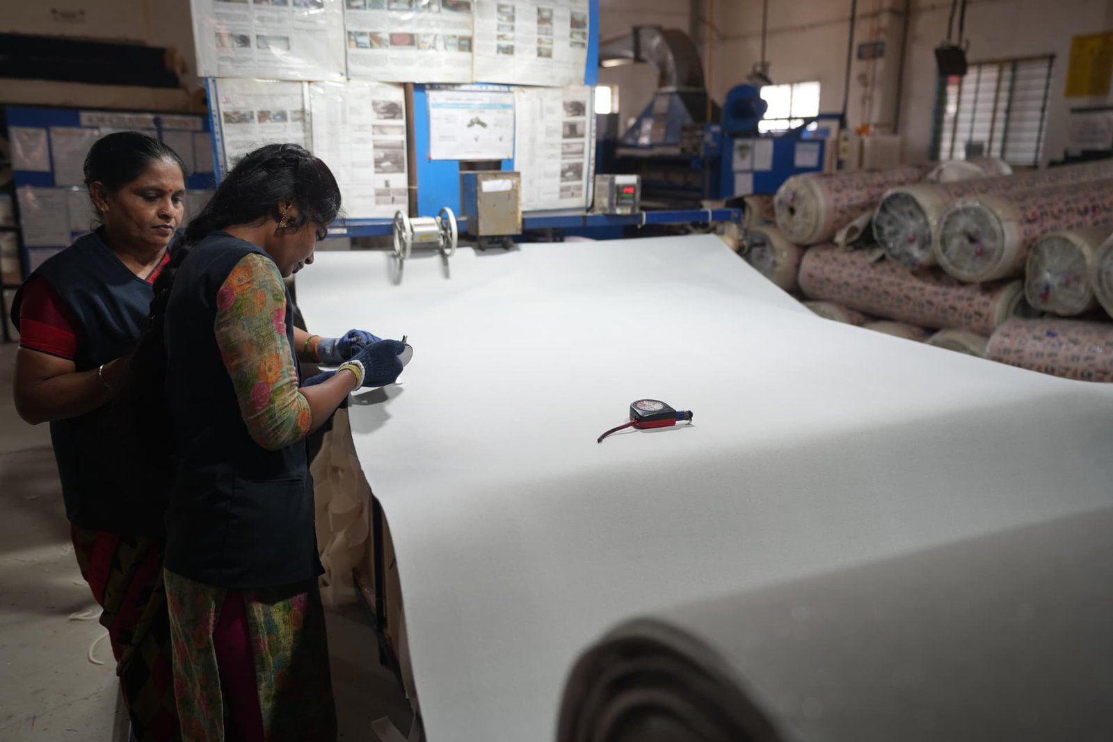 Quality control team measuring fabric thickness on a finished roll